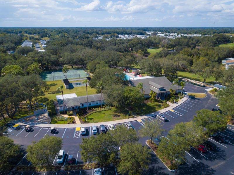 View of clubhouse parking lot with tennis courts in distance 
